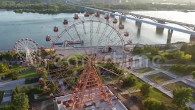 在河和城市景观上，无人机可以看到游乐园里五颜六色的摩天轮。 大型摩天轮游乐园